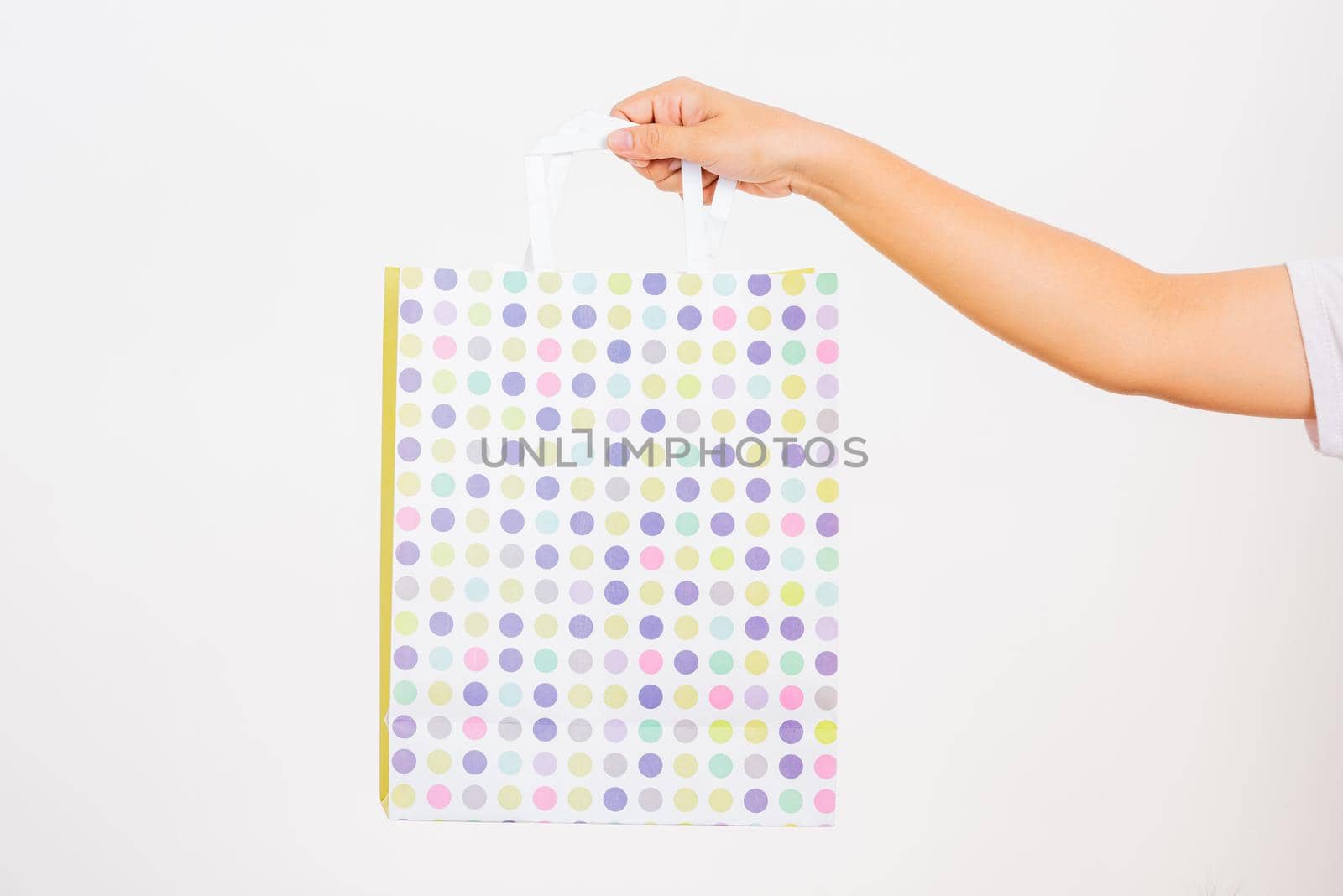 Closeup women hand holding a white circular pattern shopping bag, studio shot isolated on white background, female holds in hand white clear empty blank craft paper gift bag for purchases