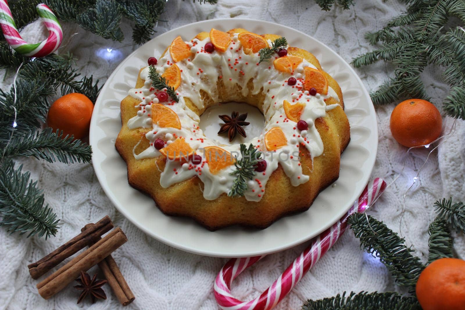 Around cupcake on a plate is decorated with a slice of tangerine and a pine twig