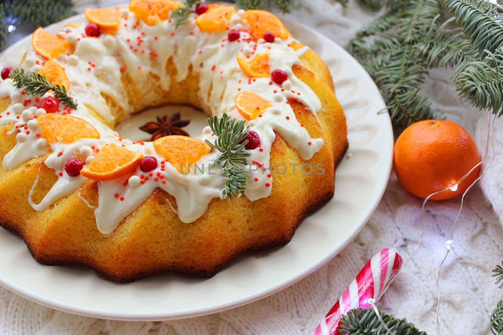 A round shaped piece of Christmas cake decorated with slices of tangerine and fir branches