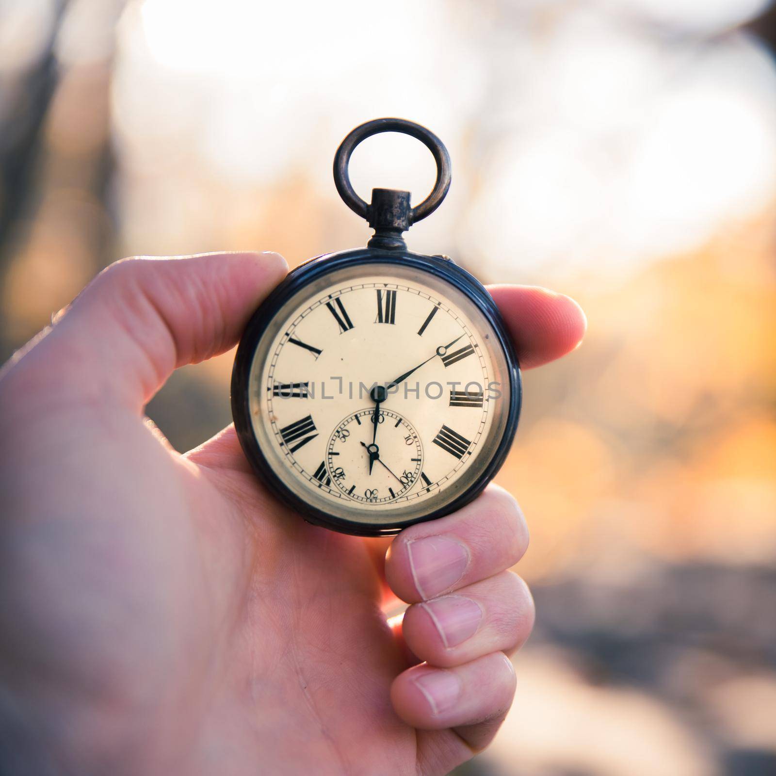 Hand held stop watch outdoors, autumn, blurry background