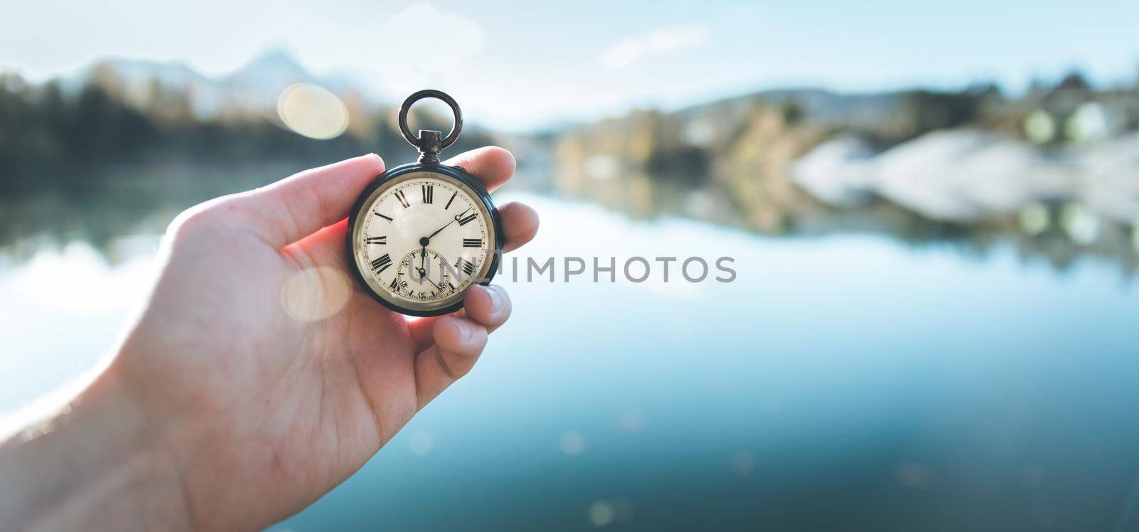 Vintage watch hand-held, autumwn view with lake and trees in the background by Daxenbichler