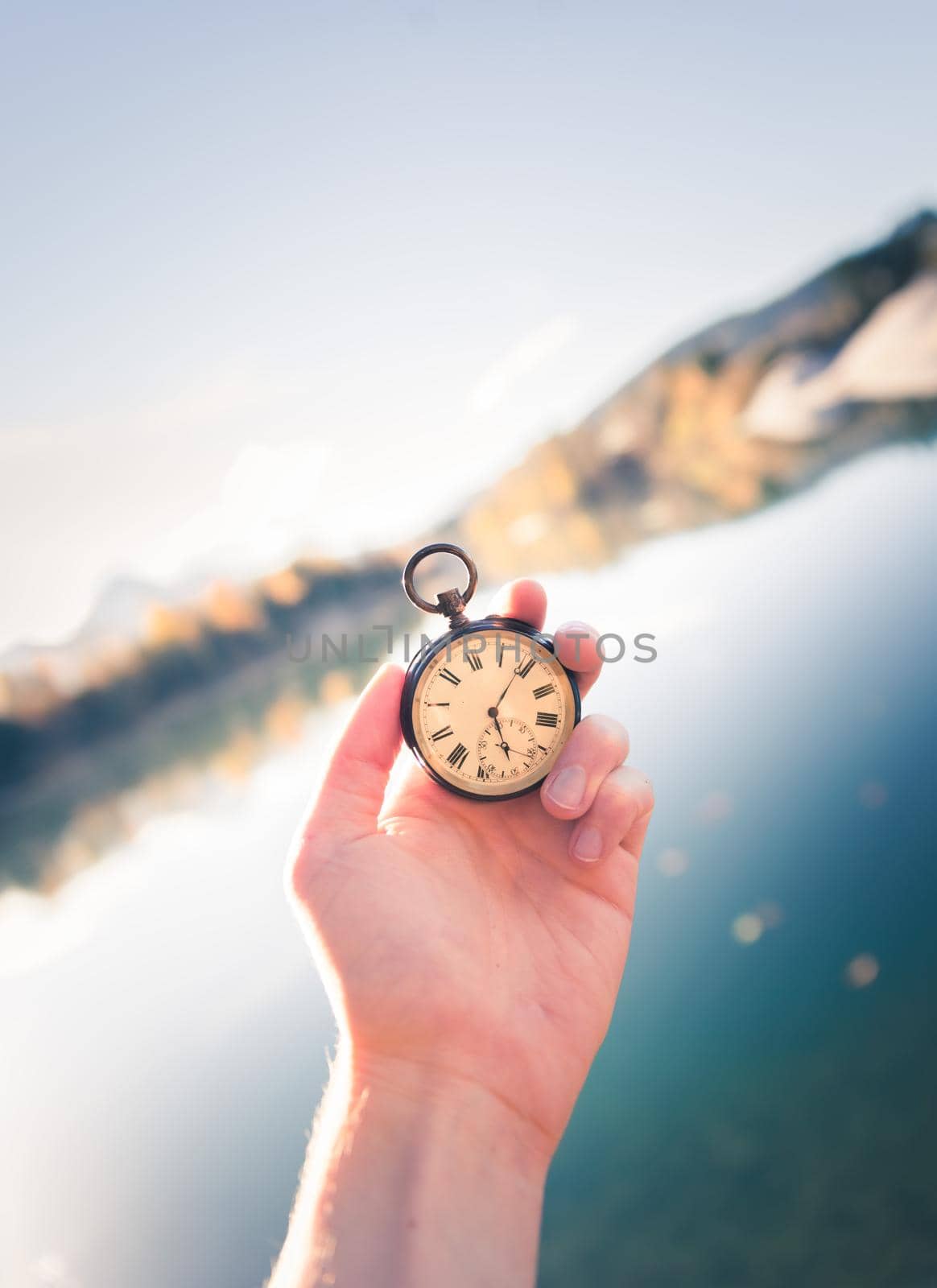 Vintage watch hand-held, autumwn view with lake and trees in the background by Daxenbichler