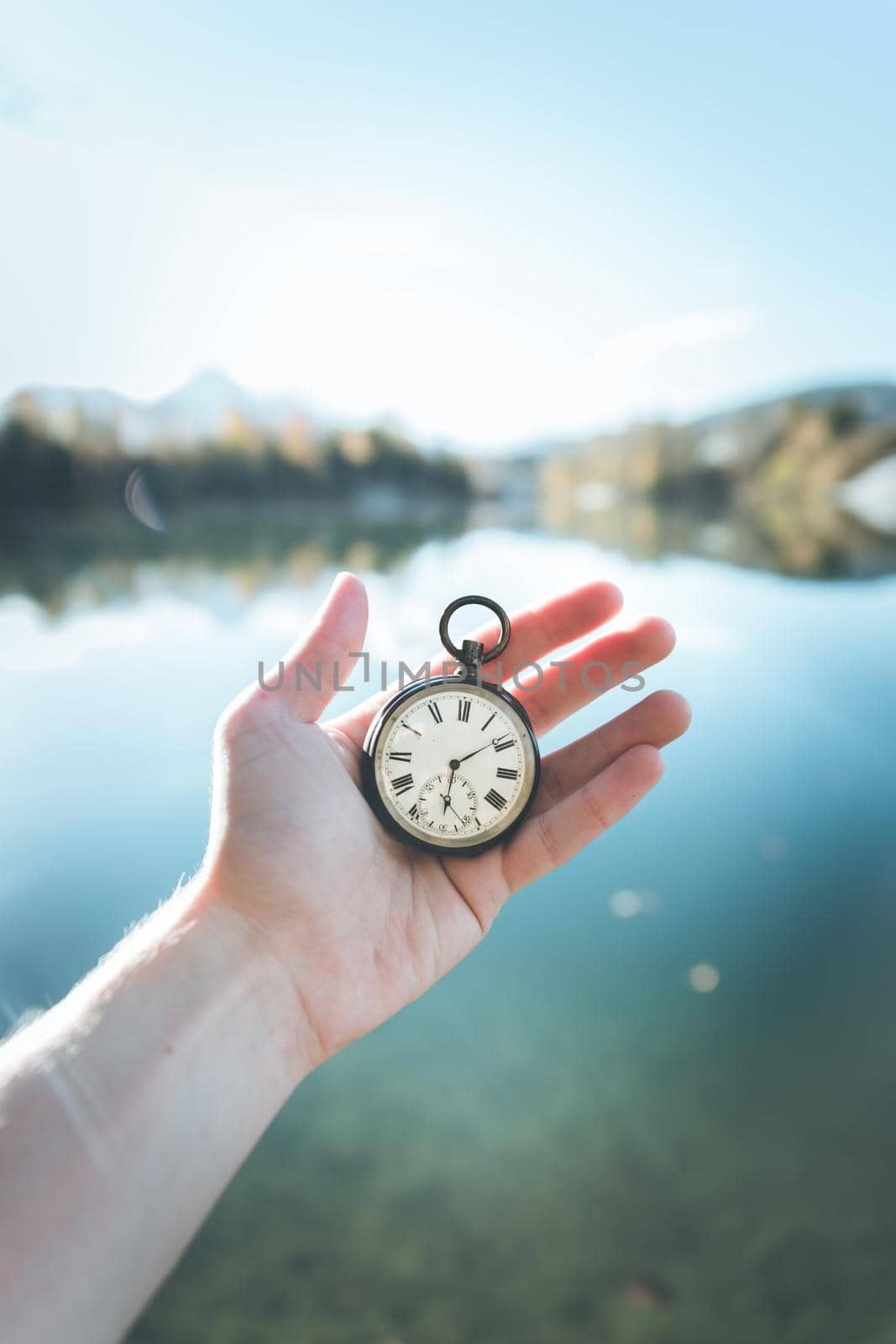 Hand held stop watch outdoors, autumn, blurry blue lake in the background