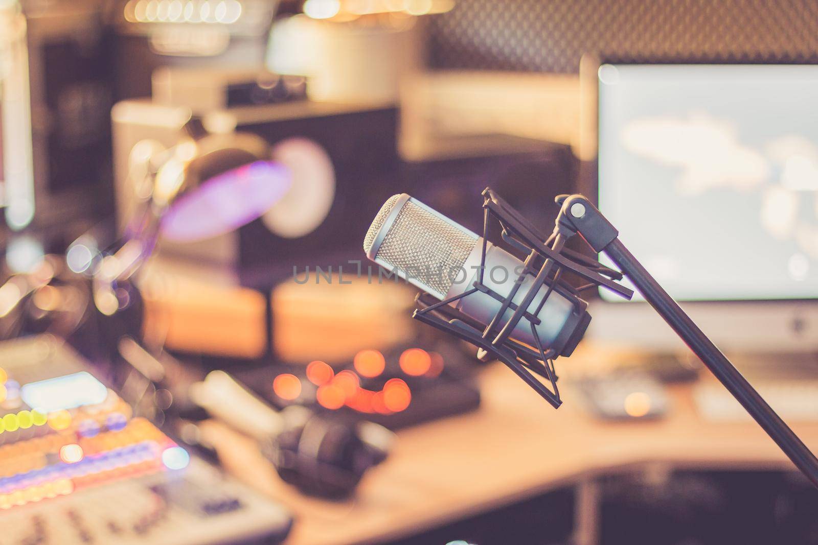 Microphone in a professional recording or radio studio, equipment in the blurry background