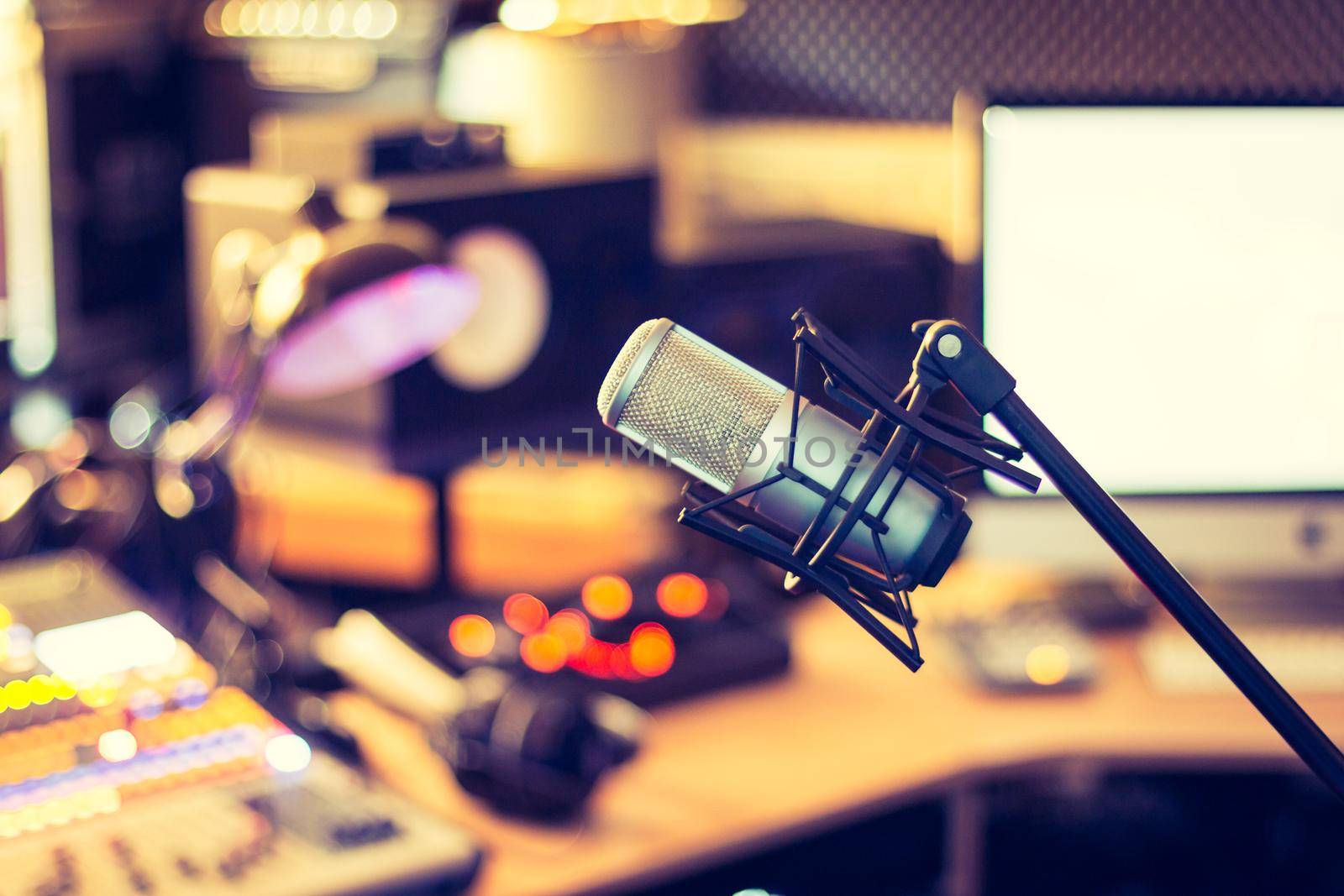 Microphone in a professional recording or radio studio, equipment in the blurry background