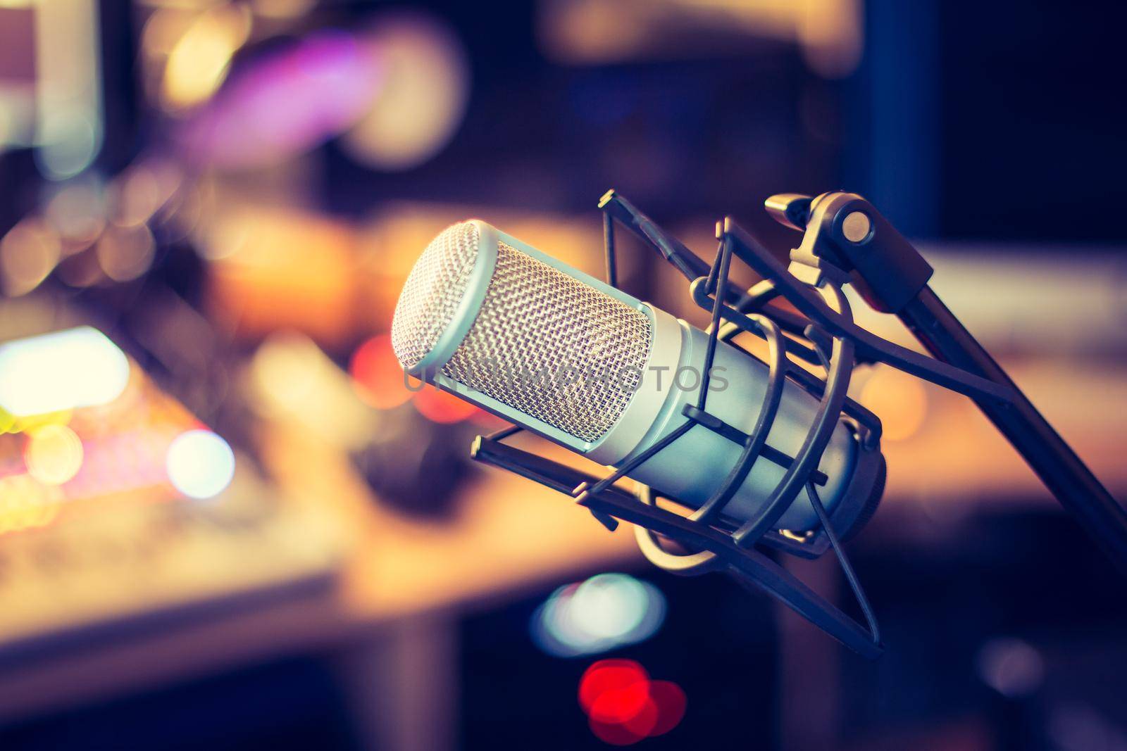 Microphone in a professional recording or radio studio, equipment in the blurry background