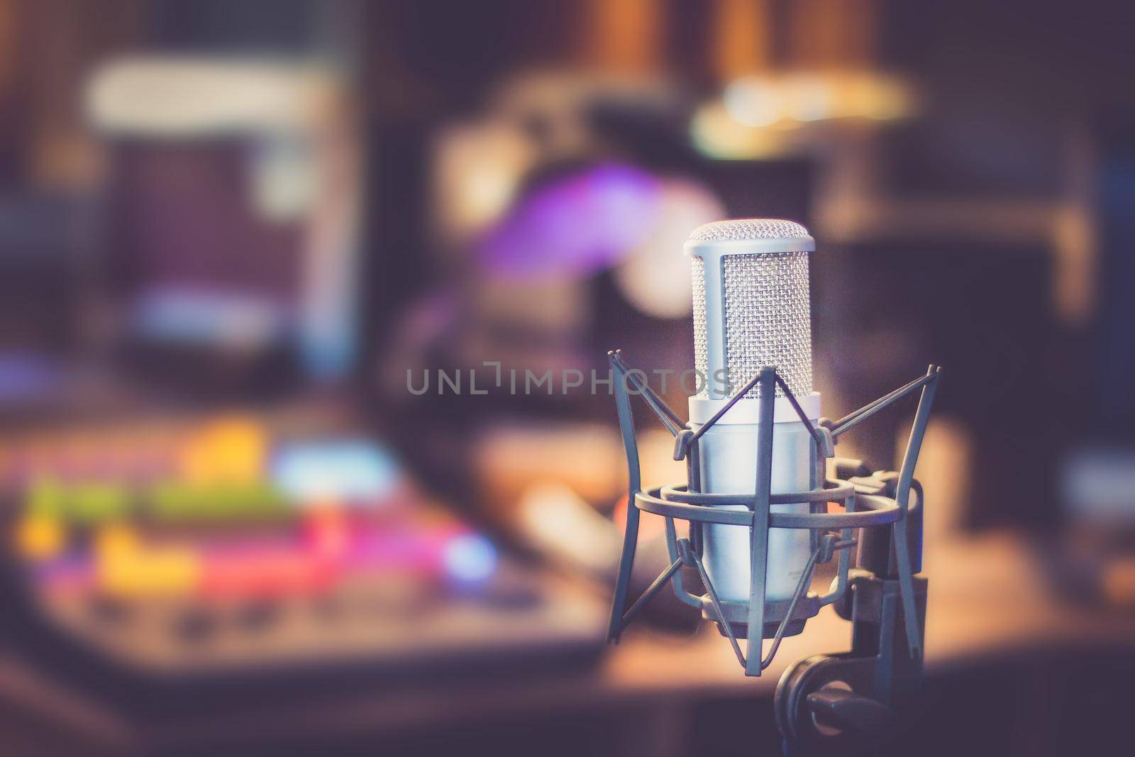 Microphone in a professional recording or radio studio, equipment in the blurry background