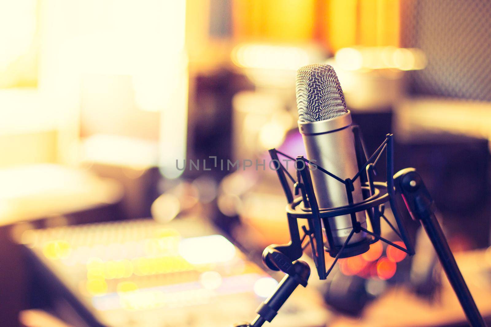 Microphone in a professional recording or radio studio, equipment in the blurry background