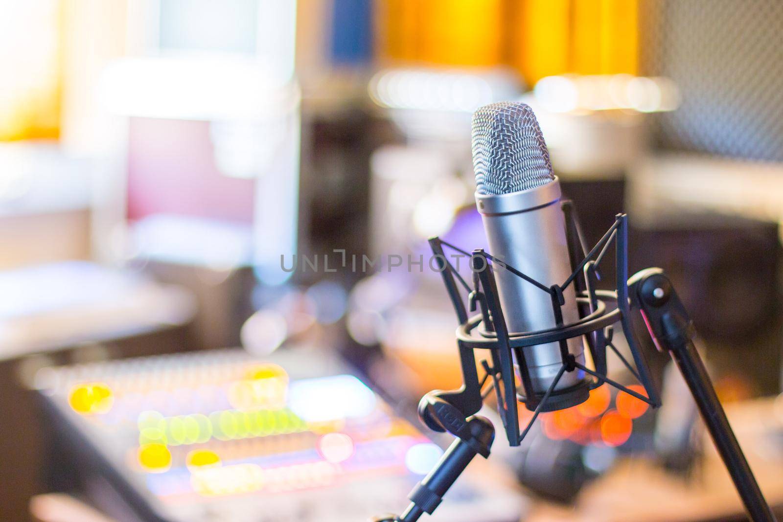 Microphone in a professional recording or radio studio, equipment in the blurry background