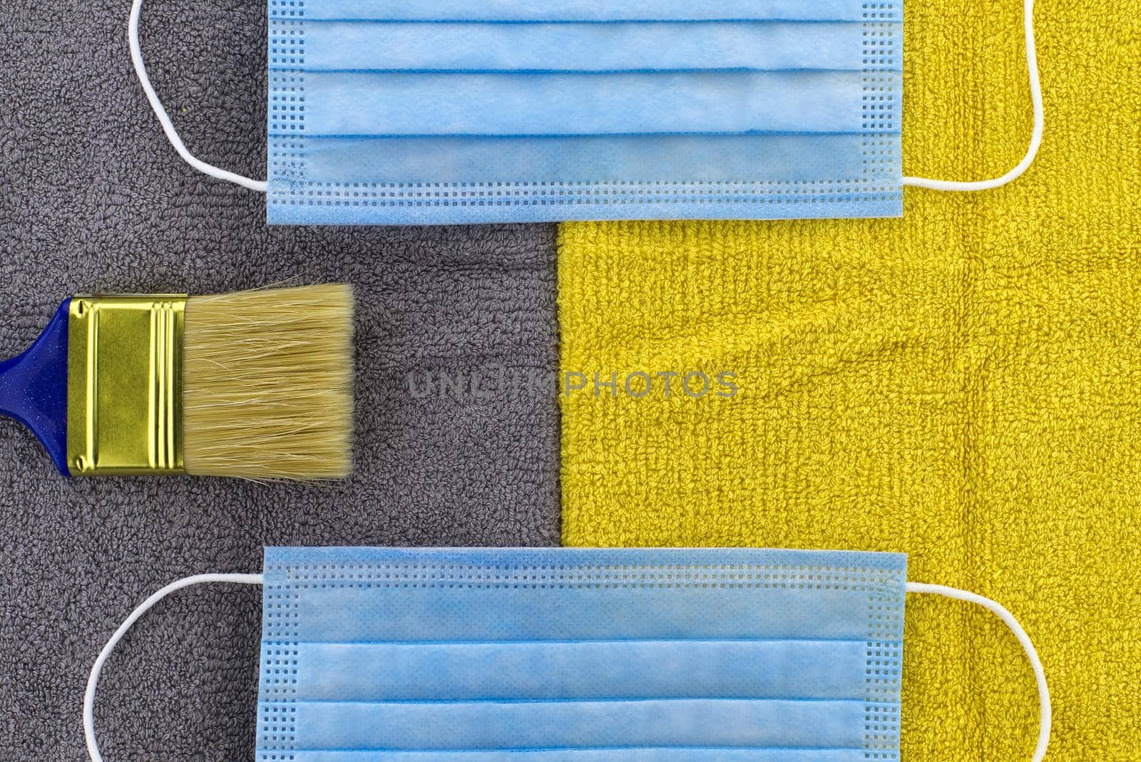 Trendy color of the year concept with clean paintbrush and protective face mask on grey - yellow textile background