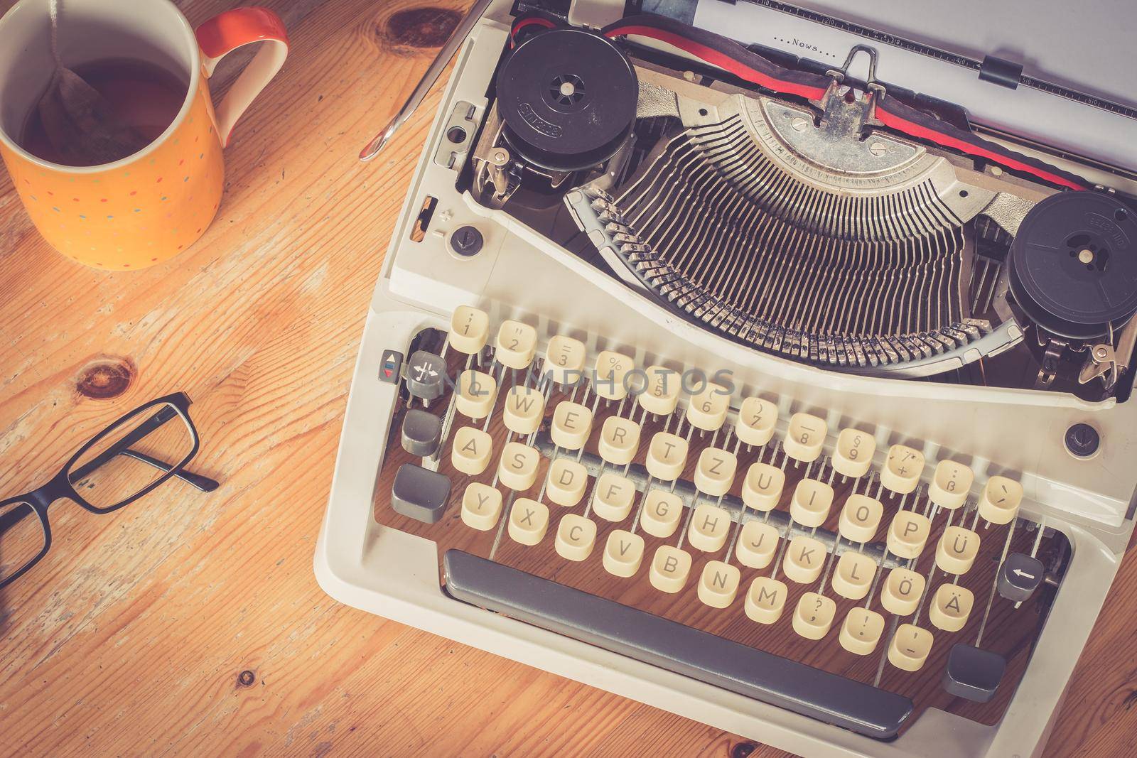 Vintage typewriter, glasses and cup of coffee on a wood desk
