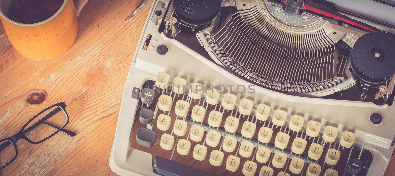 Vintage typewriter, glasses and cup of coffee on a wood desk