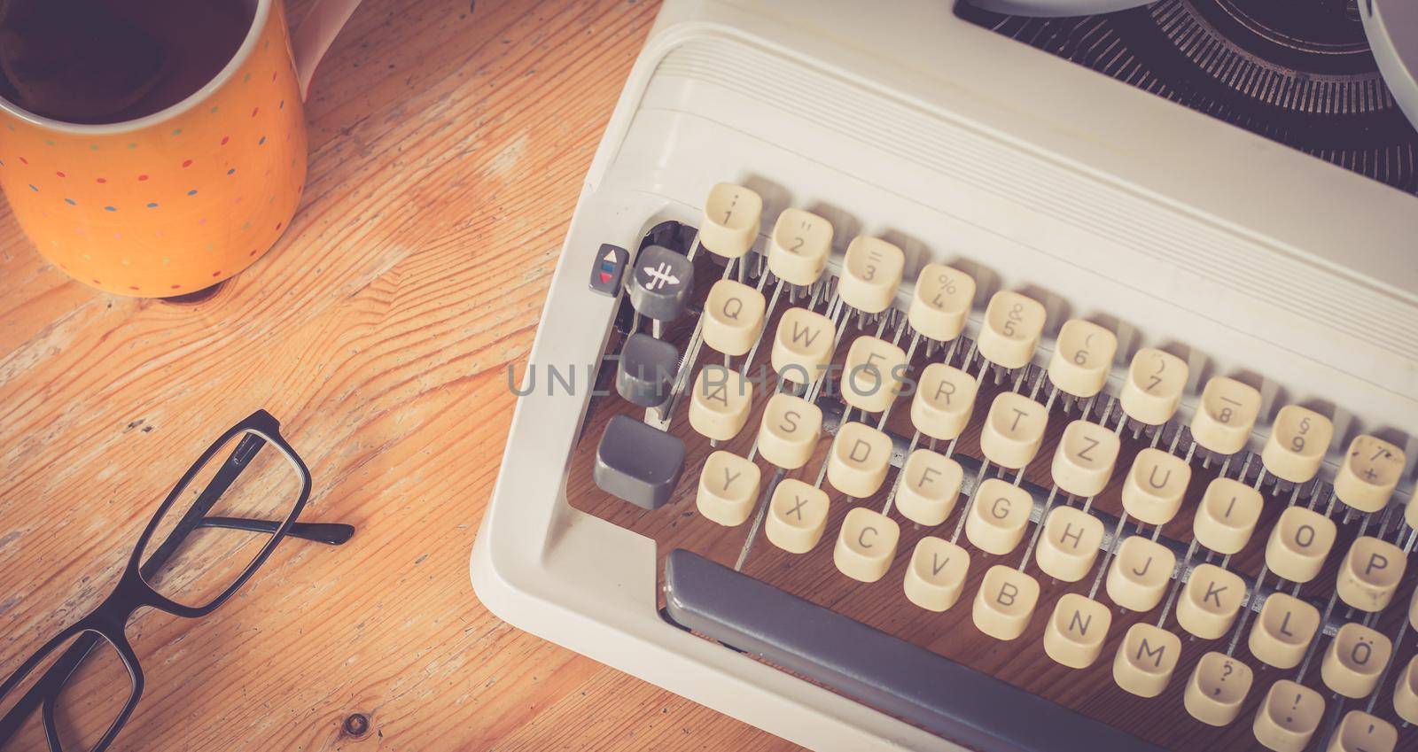 Vintage typewriter, glasses and cup of coffee on a wood desk