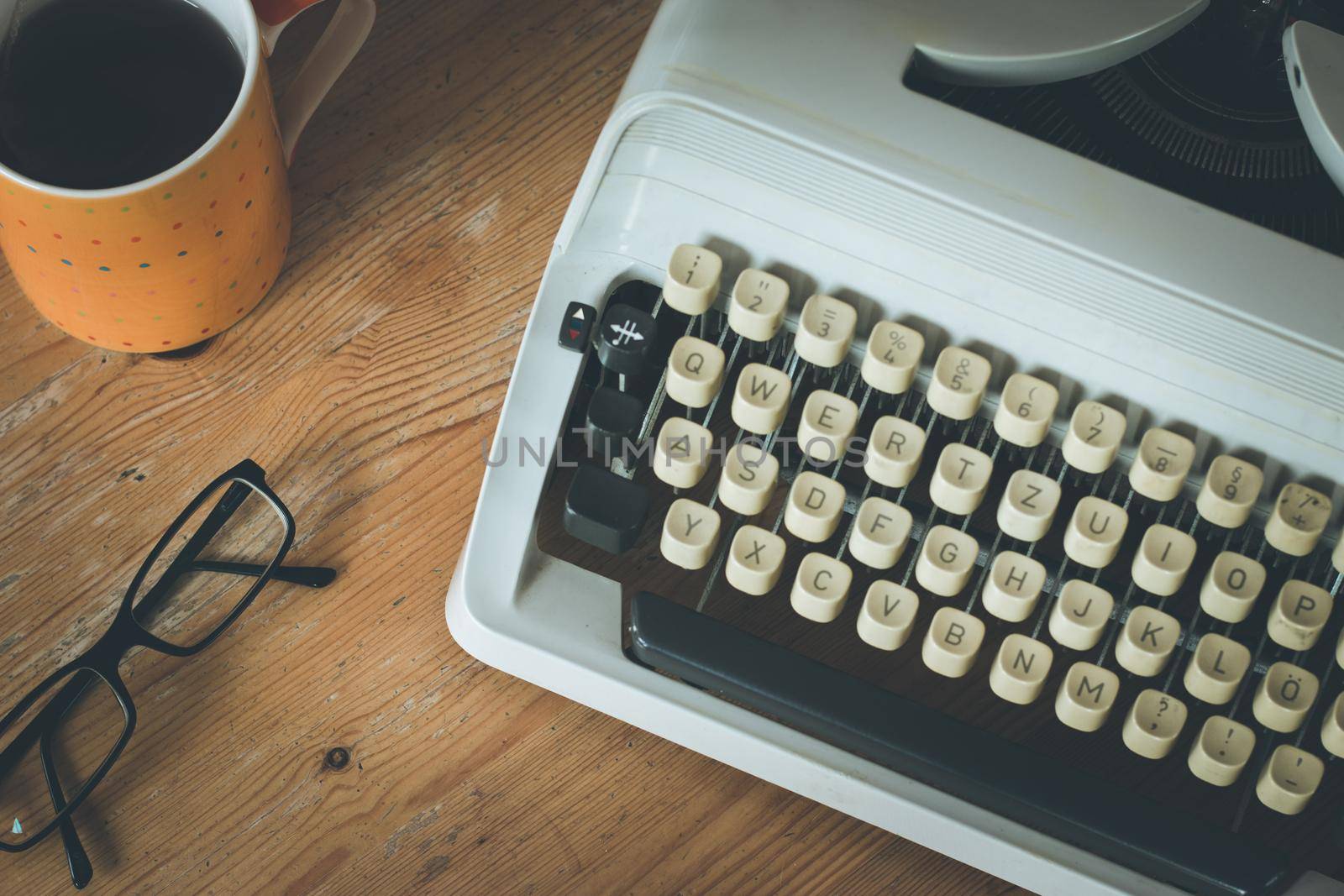 Vintage typewriter, glasses and cup of coffee on a wood desk