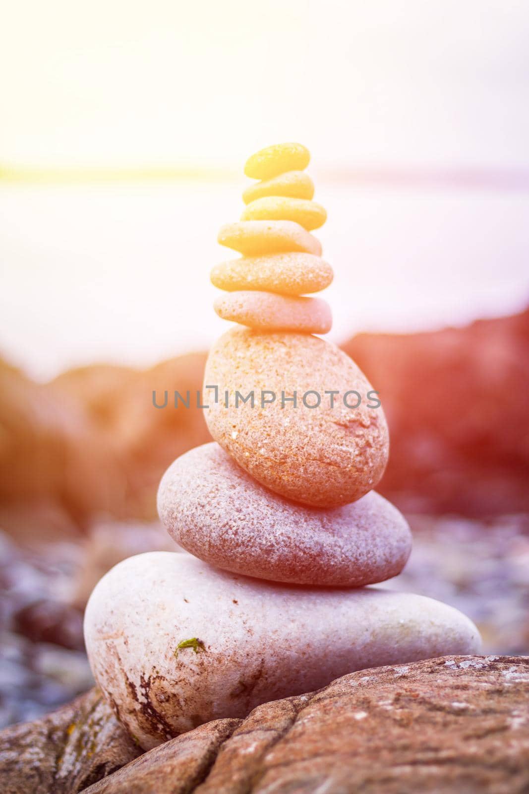 Close up picture of a stone cairn outdoors. Ocean in the blurry background. Sunshine.