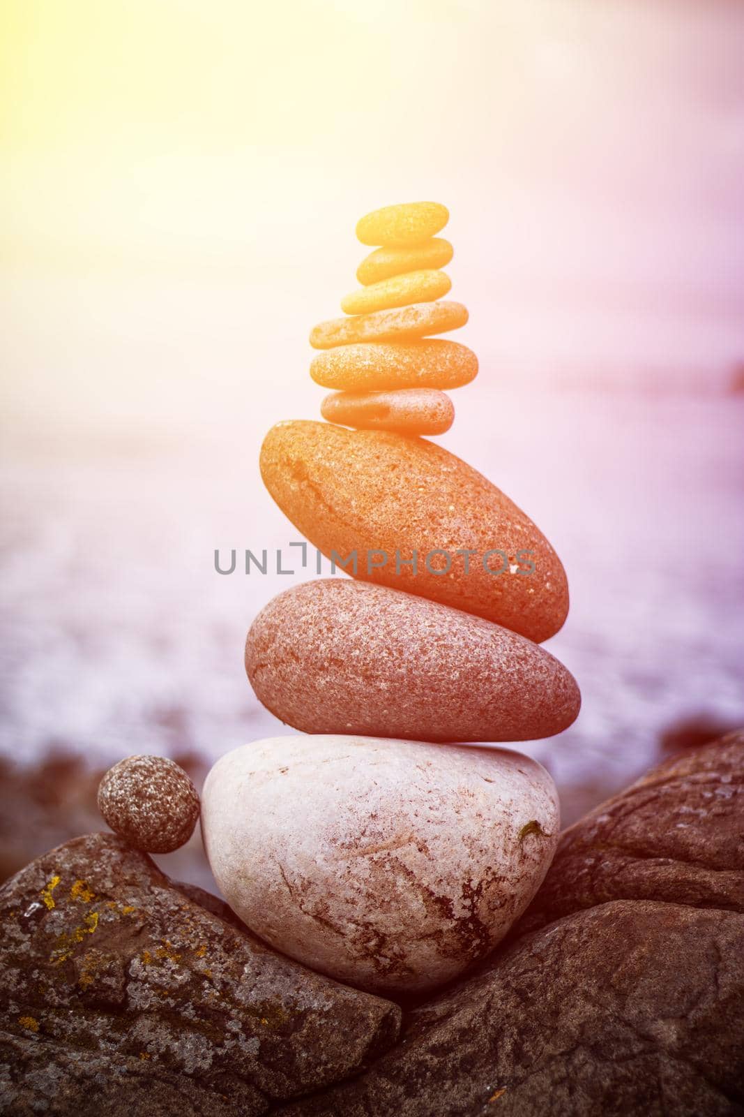 Close up picture of a stone cairn outdoors. Ocean in the blurry background. Sunshine.