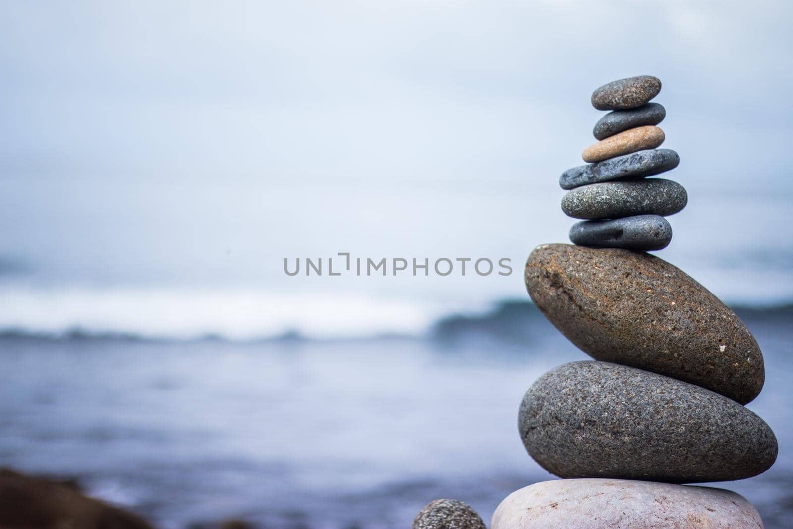 Close up picture of a stone cairn outdoors. Ocean in the blurry background