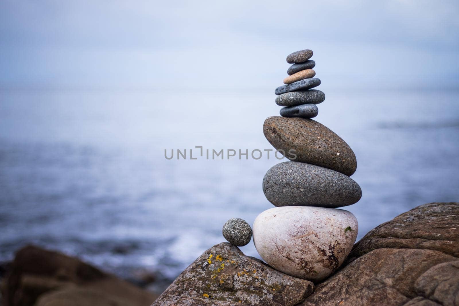 Close up picture of a stone cairn outdoors. Ocean in the blurry background