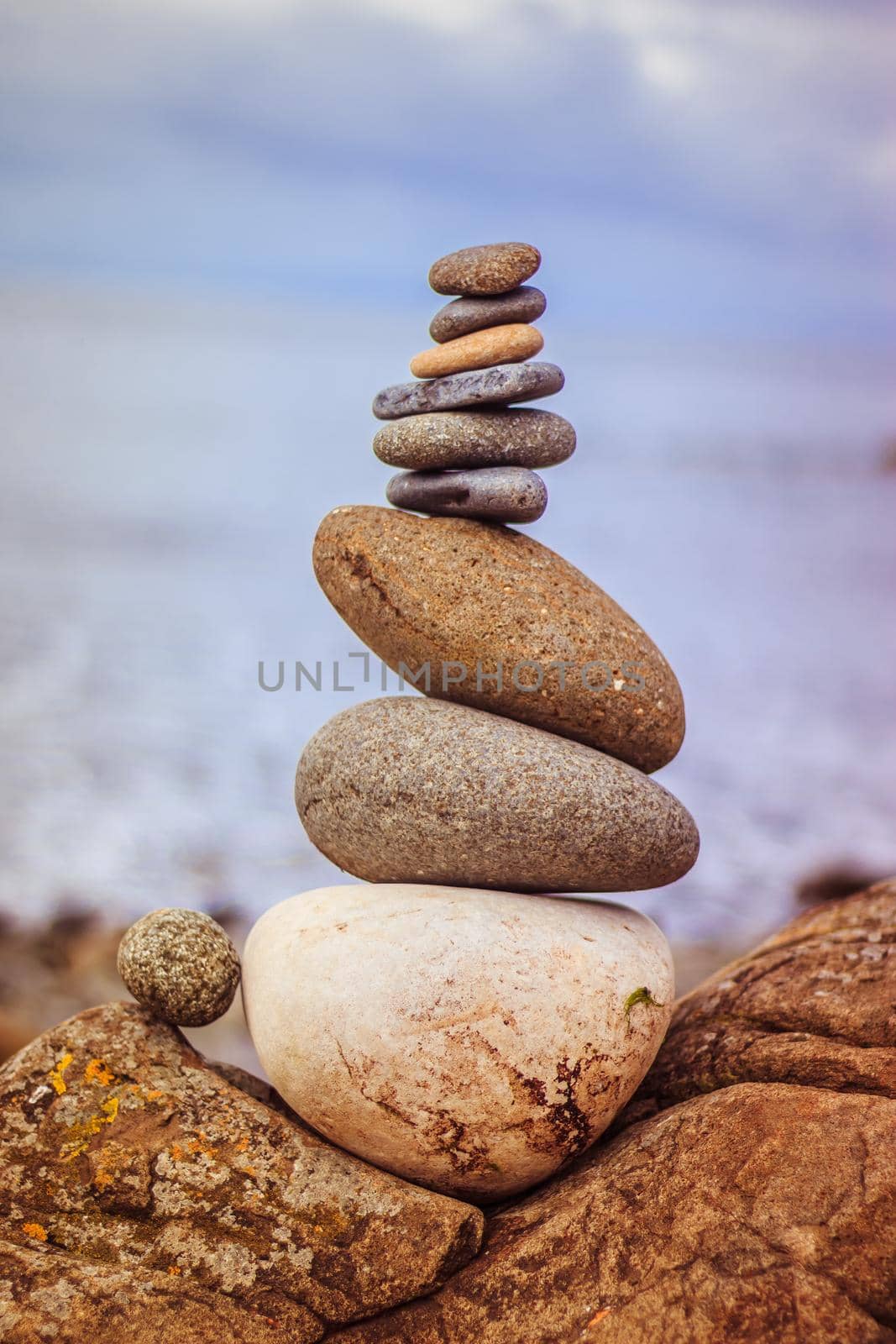 Close up picture of a stone cairn outdoors. Ocean in the blurry background