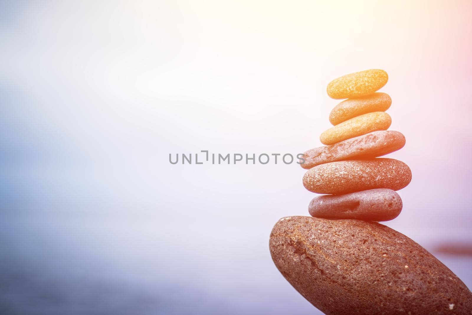 Close up picture of a stone cairn outdoors. Ocean in the blurry background. Sunshine.