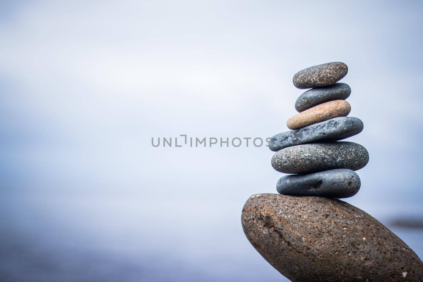 Balance, relaxation and wellness: Stone cairn outside, ocean in the blurry background by Daxenbichler