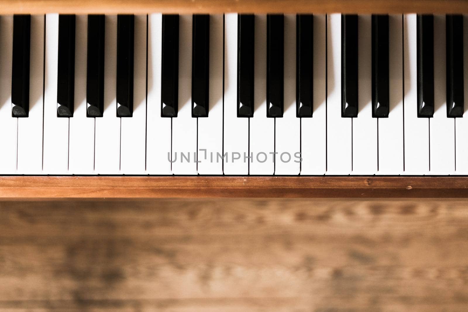 Vintage wooden piano. Keys in the foreground, wooden floor in the blurry background