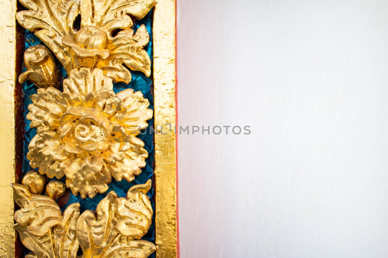 The floral patterns on the temple walls are decorated in beautiful gold. It is an architectural work of a temple in Thailand.