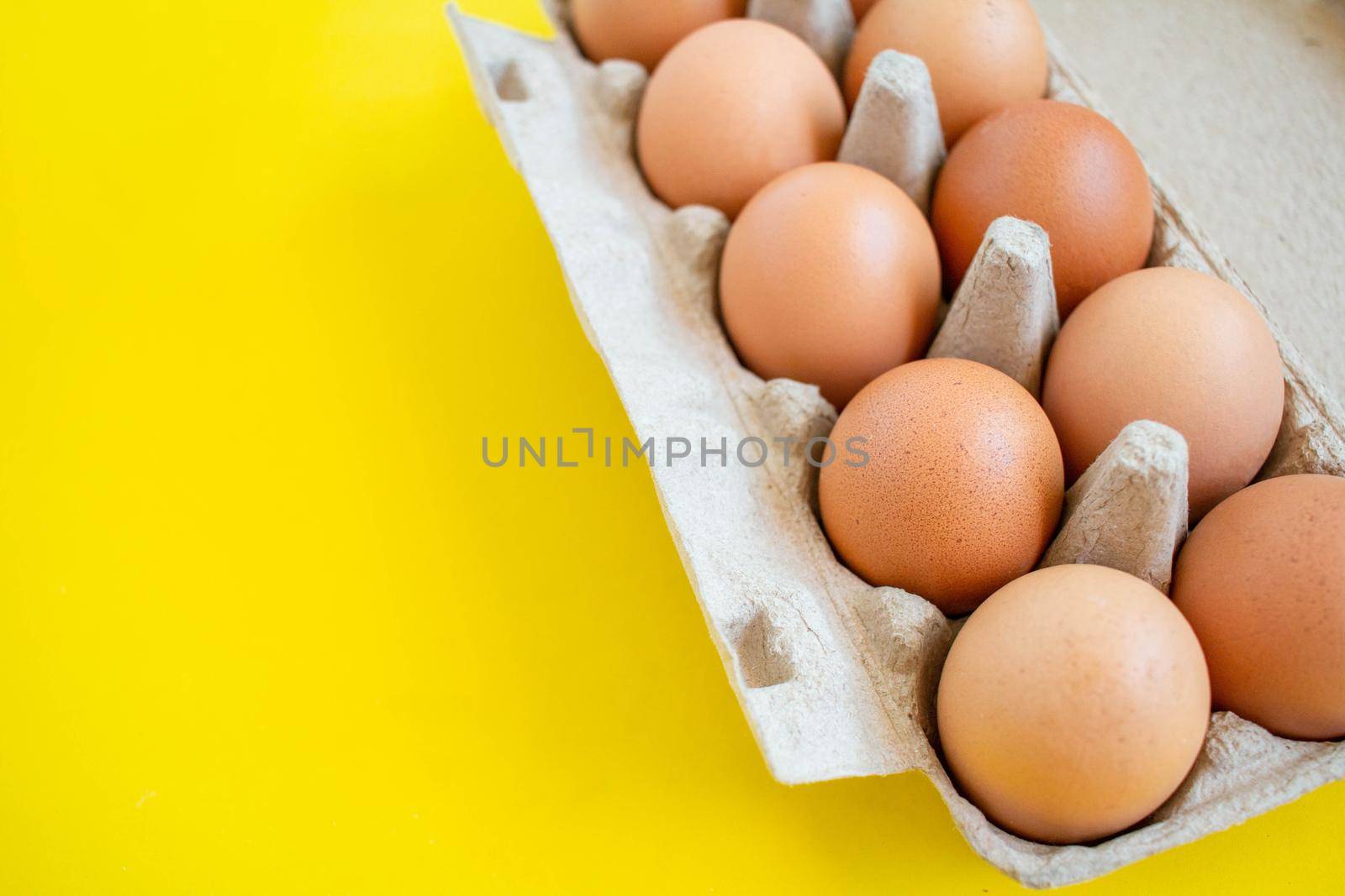 Closeup brown eggs in paper box A box full of eggs Bought from supermarket placed on a yellow background