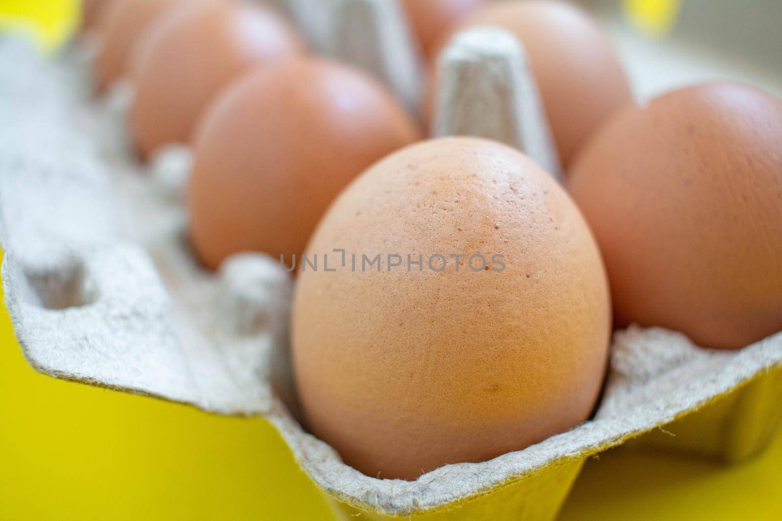 Closeup brown eggs in paper box A box full of eggs Bought from supermarket placed on a yellow background