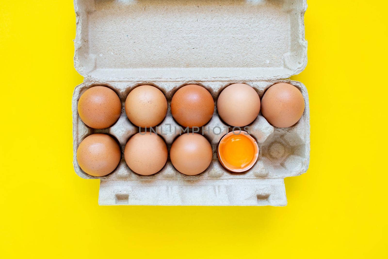 Closeup cracked brown eggs And eggs in paper boxes Placed side by side on a yellow background.