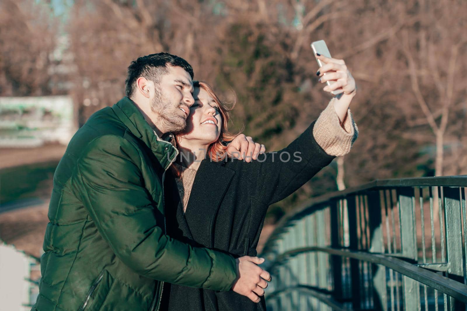 Cheerful Young Couple Making Selfie on the Bridge. Two Happy People Love Story on the Street