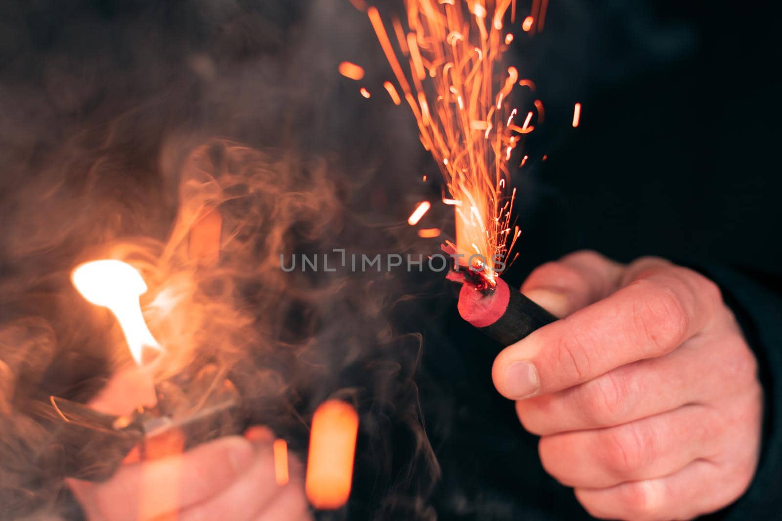 The Firecracker in a Hand. Man Holding a Burning Petard in His Hand. A Human with a Pyrotechnics that Burns with Sparks and Smoke Outdoors