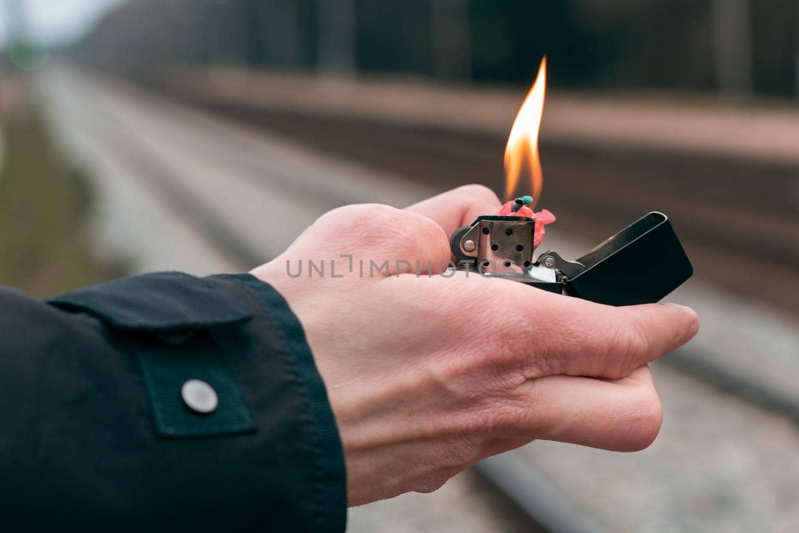 Setting Fire to the Firecracker. Man in Black Clothes Lighting Up the Petard. Firing Up the Pyrotechnics with a Black Gasoline Lighter Outdoors