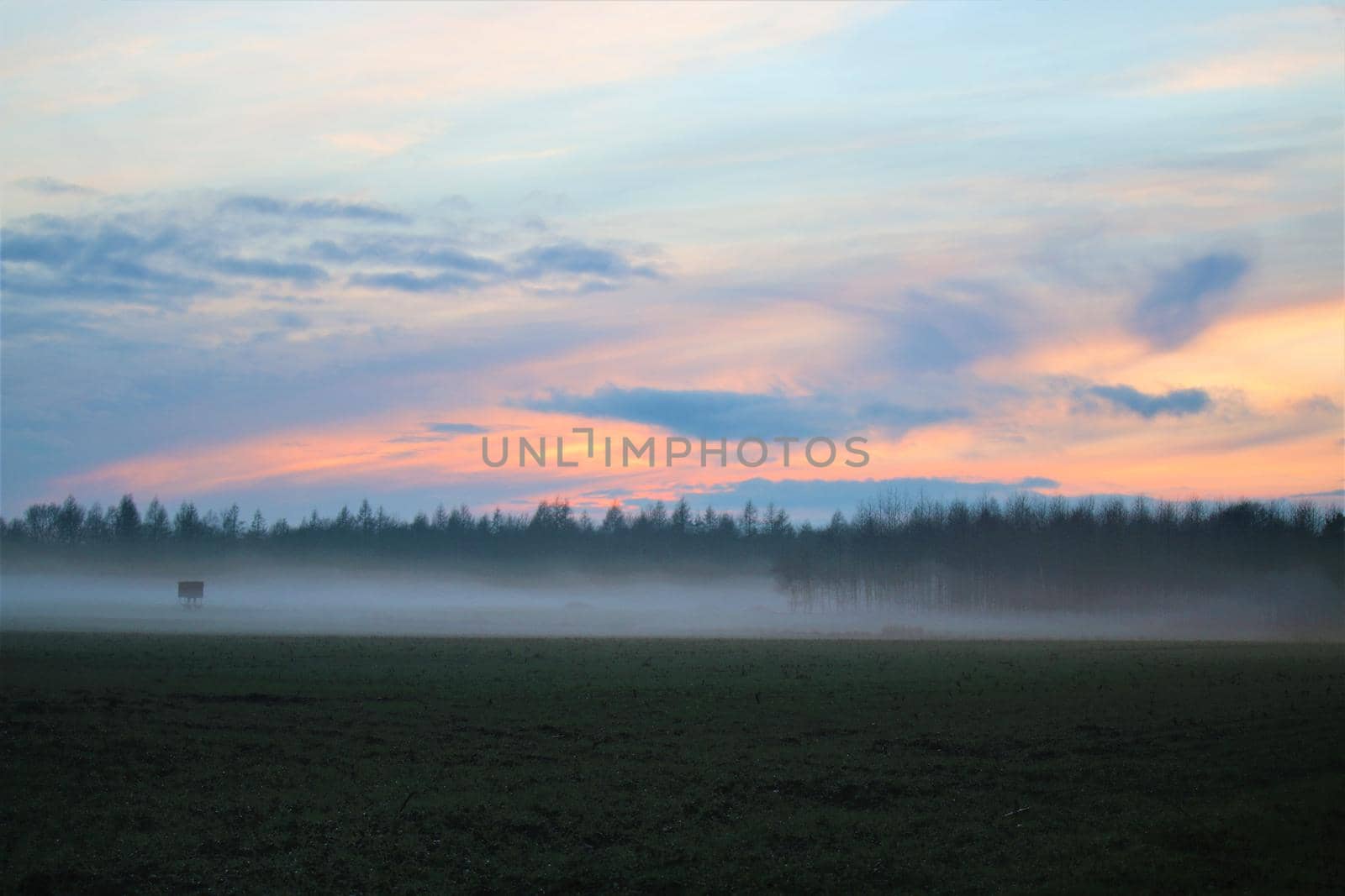 A landscape in the evening with fog and sunset