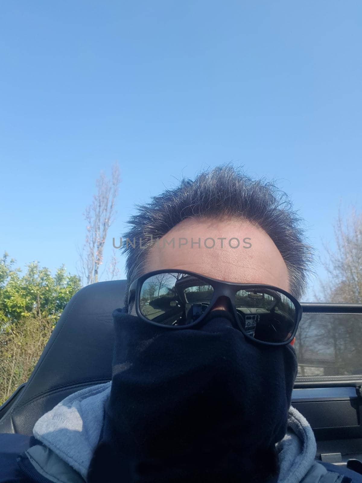 Man with face mask and sunglasses sits in convertible       by JFsPic