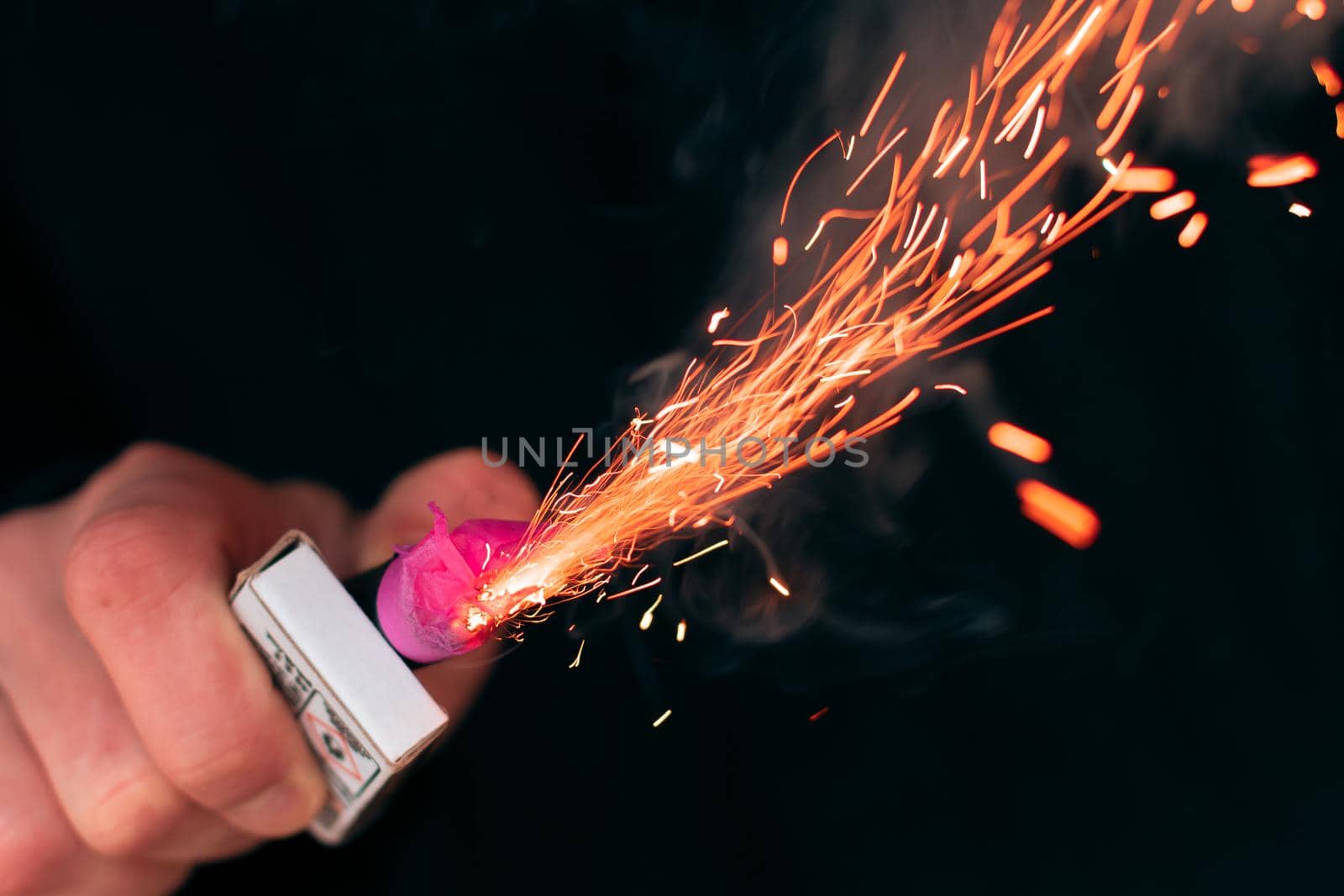 The Firecracker in a Hand. Man Holding a Burning Petard in His Hand. A Human with a Pyrotechnics that Burns with Sparks and Smoke Outdoors