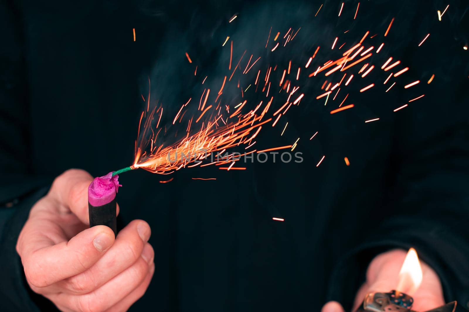 The Firecracker in a Hand. Man Holding a Burning Petard in His Hand. A Human with a Pyrotechnics that Burns with Sparks and Smoke Outdoors