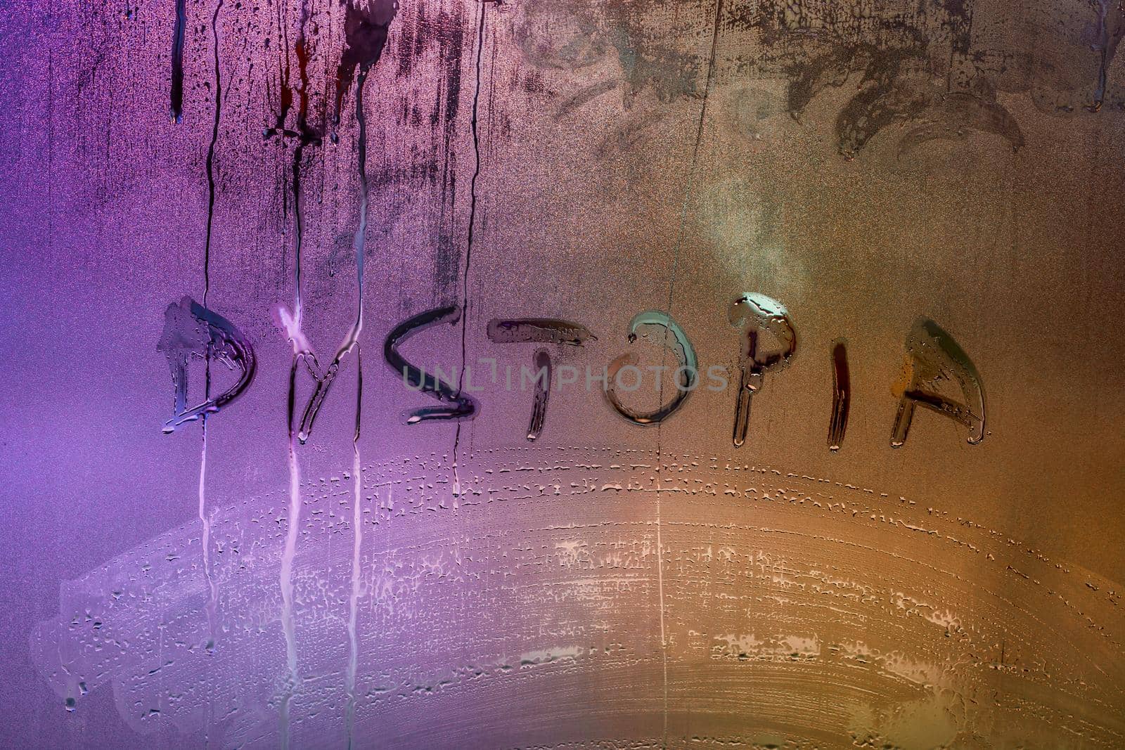 the word dystopia handwritten on wet window glass surface close-up with selective focus and pink-orange color gradient