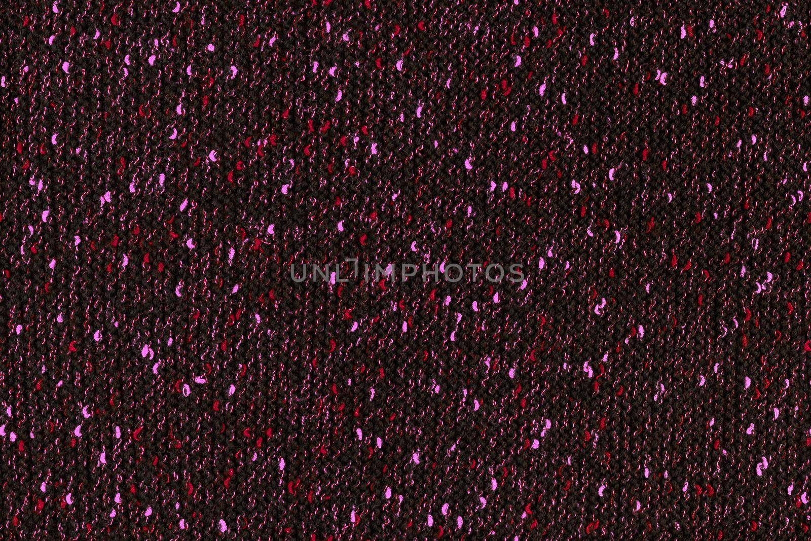 black melange manually knitted fabric with red and pink blotches - seamless texture and flat background.