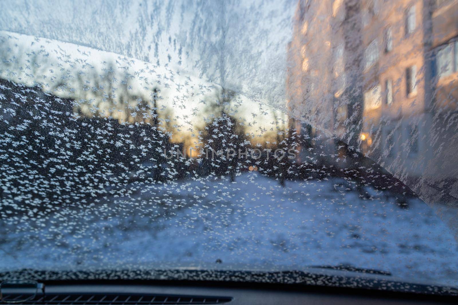Morning car windshield with frost and snowflakes, view from inside. Close-up with selective focus.