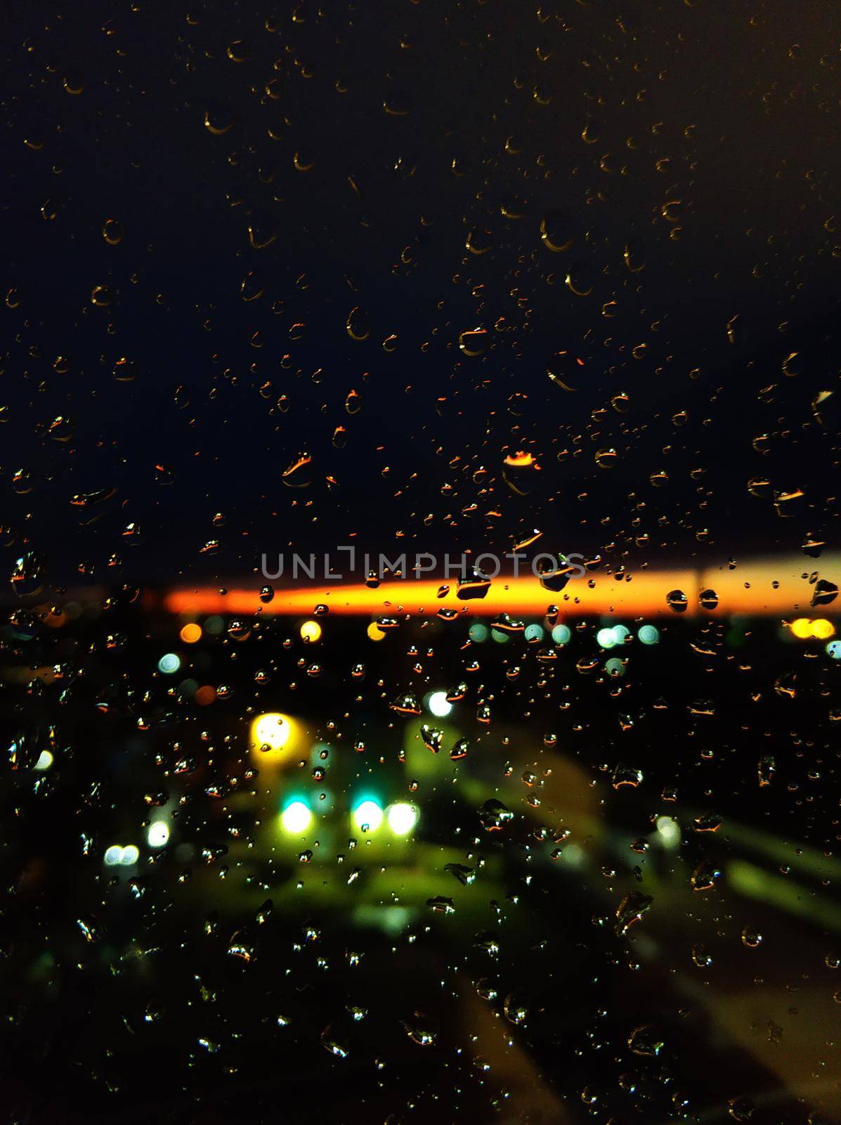 Raindrops on glass. Livin during sunset. Night sky with a bright orange stripe.