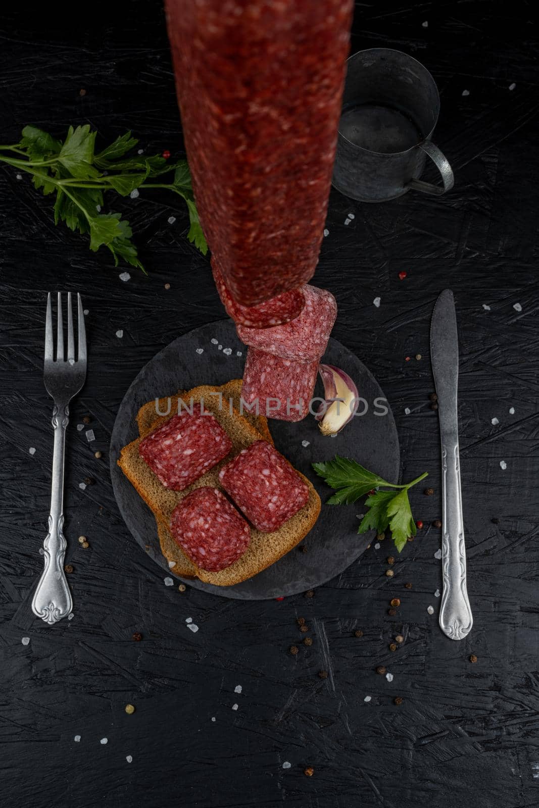 Smoked appetizing sausages on a wooden board on a black background. On a black background, sea salt