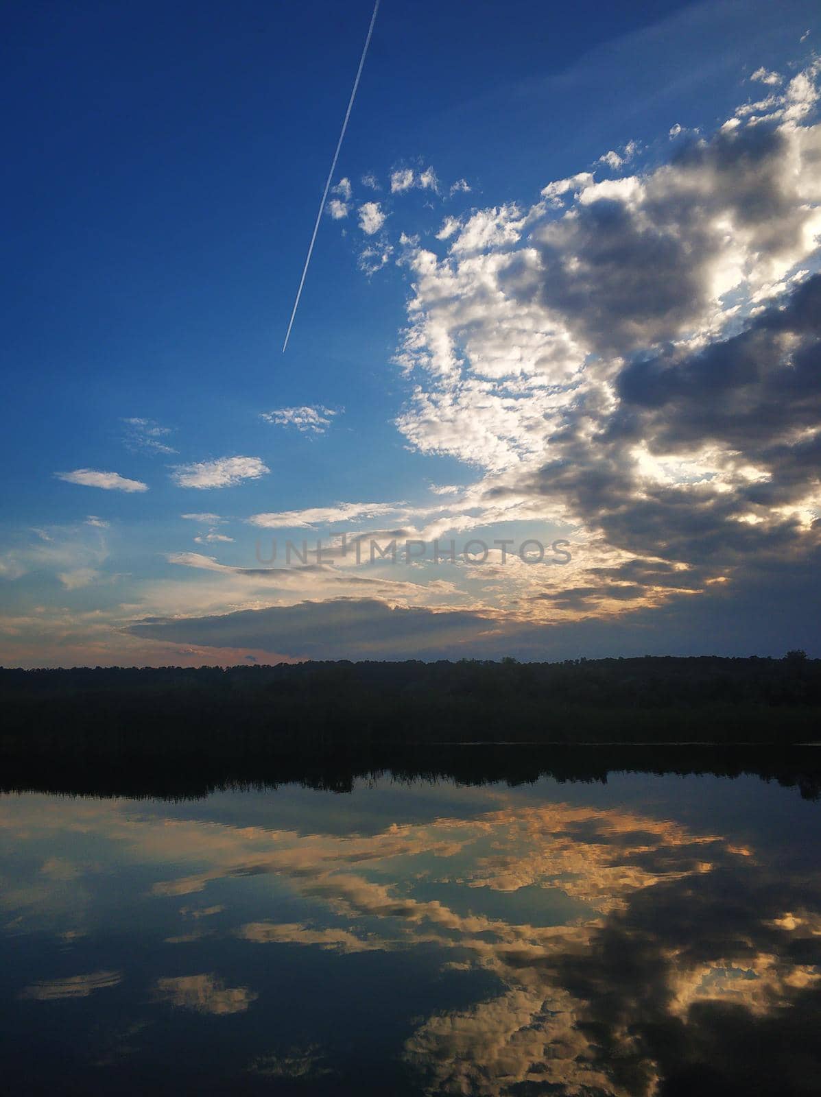 Natural landscape. Sunset over water, reflection of the sun and clouds in the water.