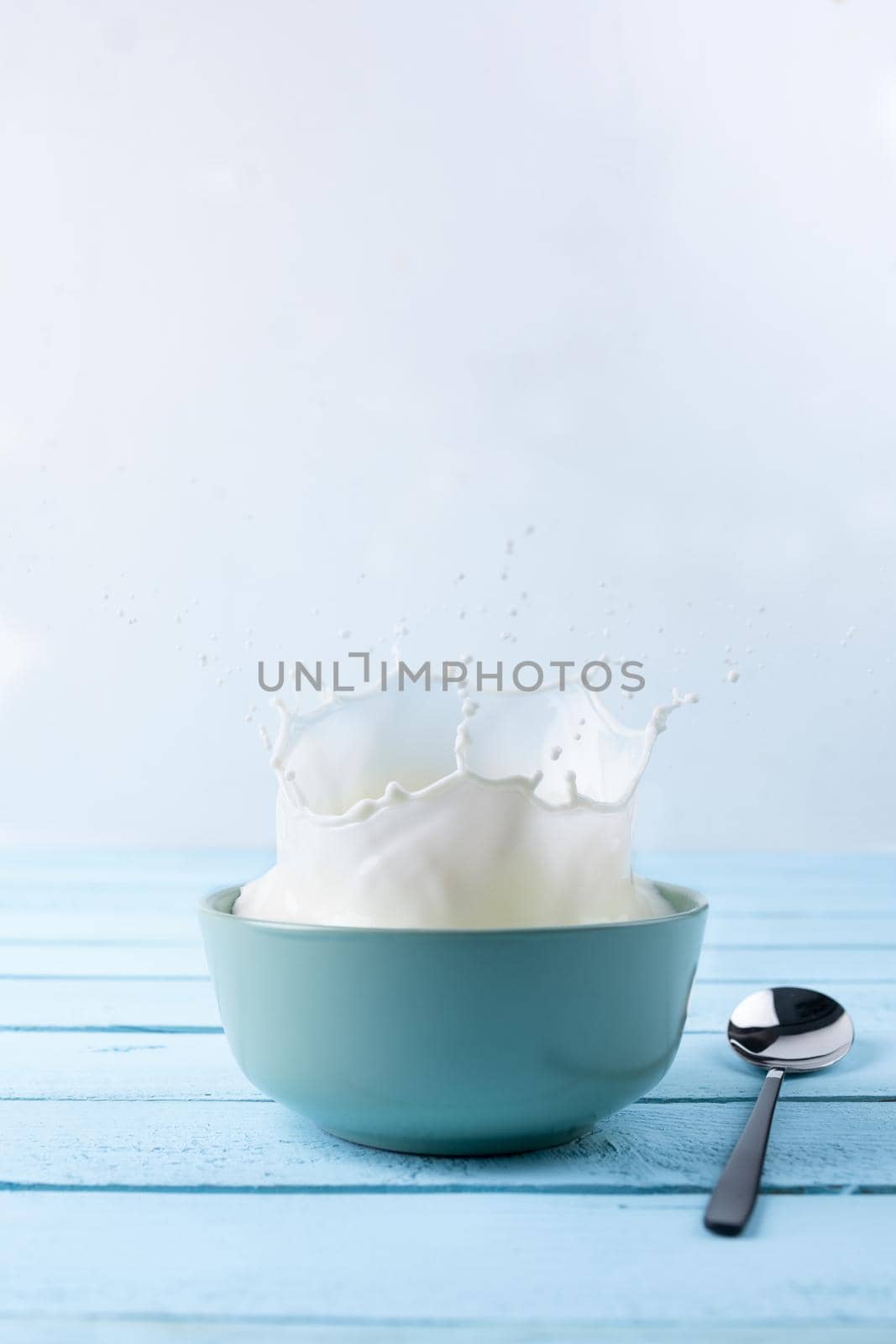 Splash of milk from the dish on a blue wooden background