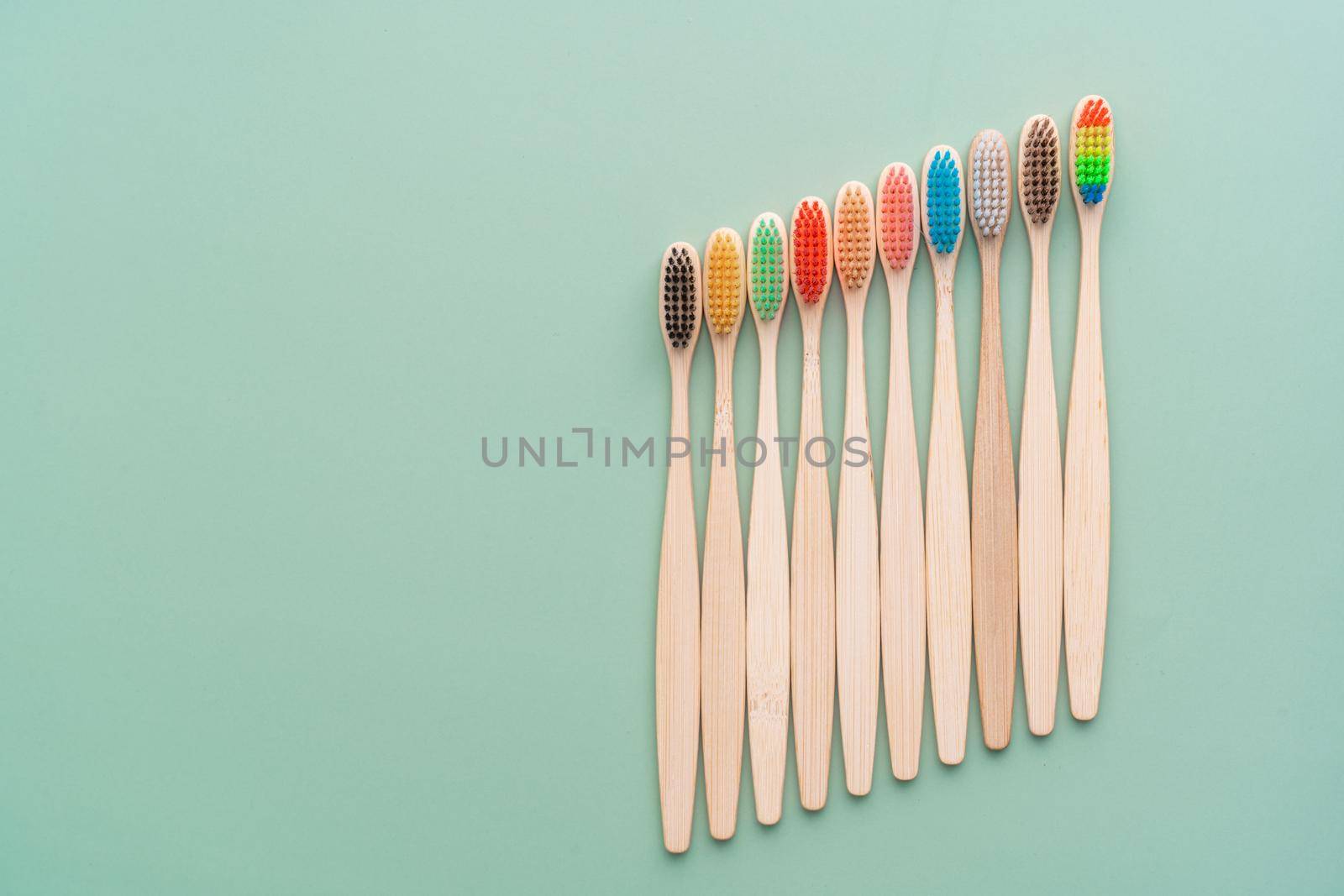 A set of Eco-friendly antibacterial toothbrushes made of bamboo wood on a light green background. Environmental care trends.