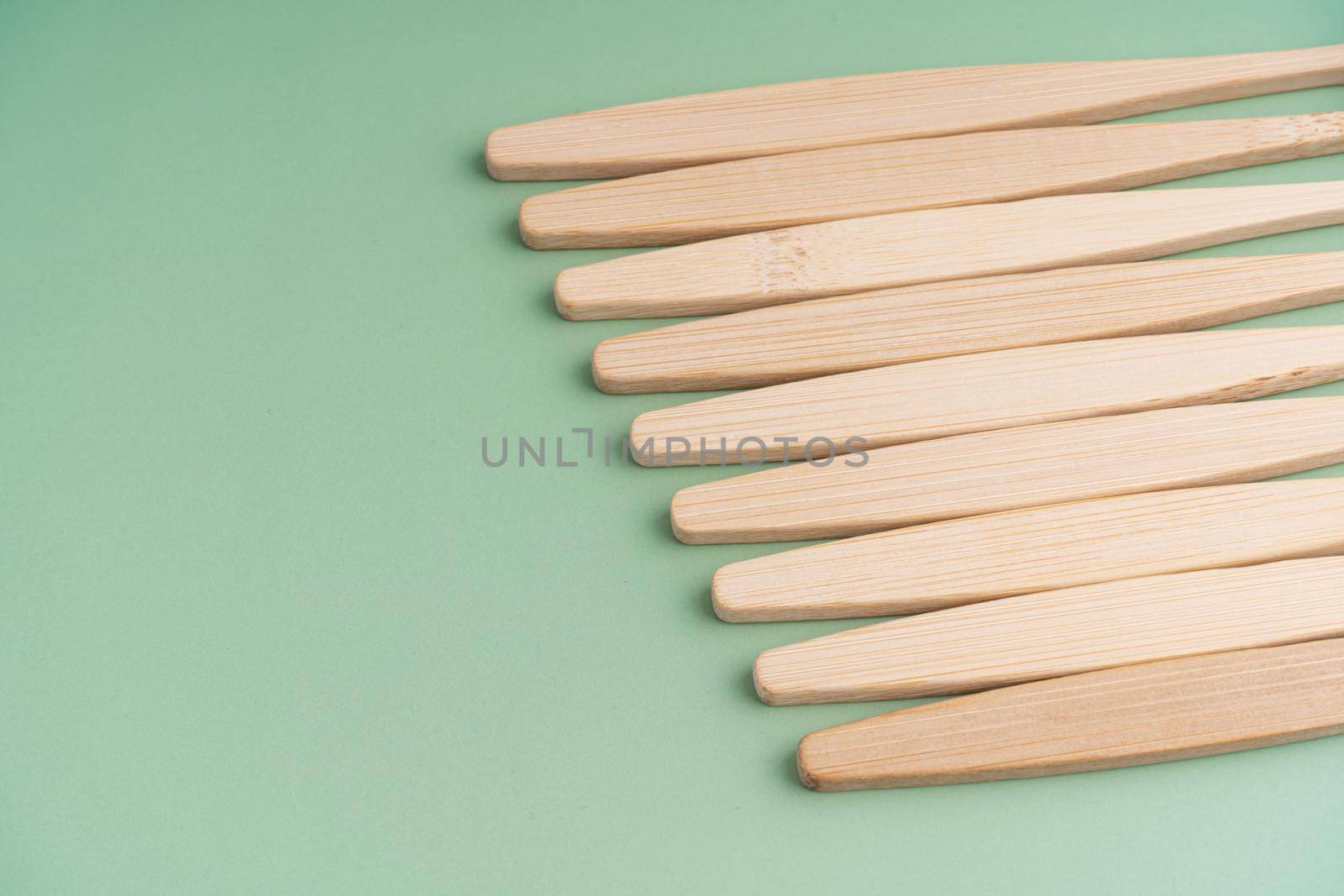 A set of Eco-friendly antibacterial toothbrushes made of bamboo wood on a light green background. Environmental care trends.