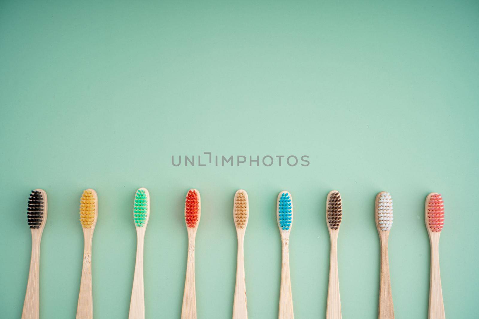 A set of Eco-friendly antibacterial toothbrushes made of bamboo wood on a light green background. Environmental care trends.