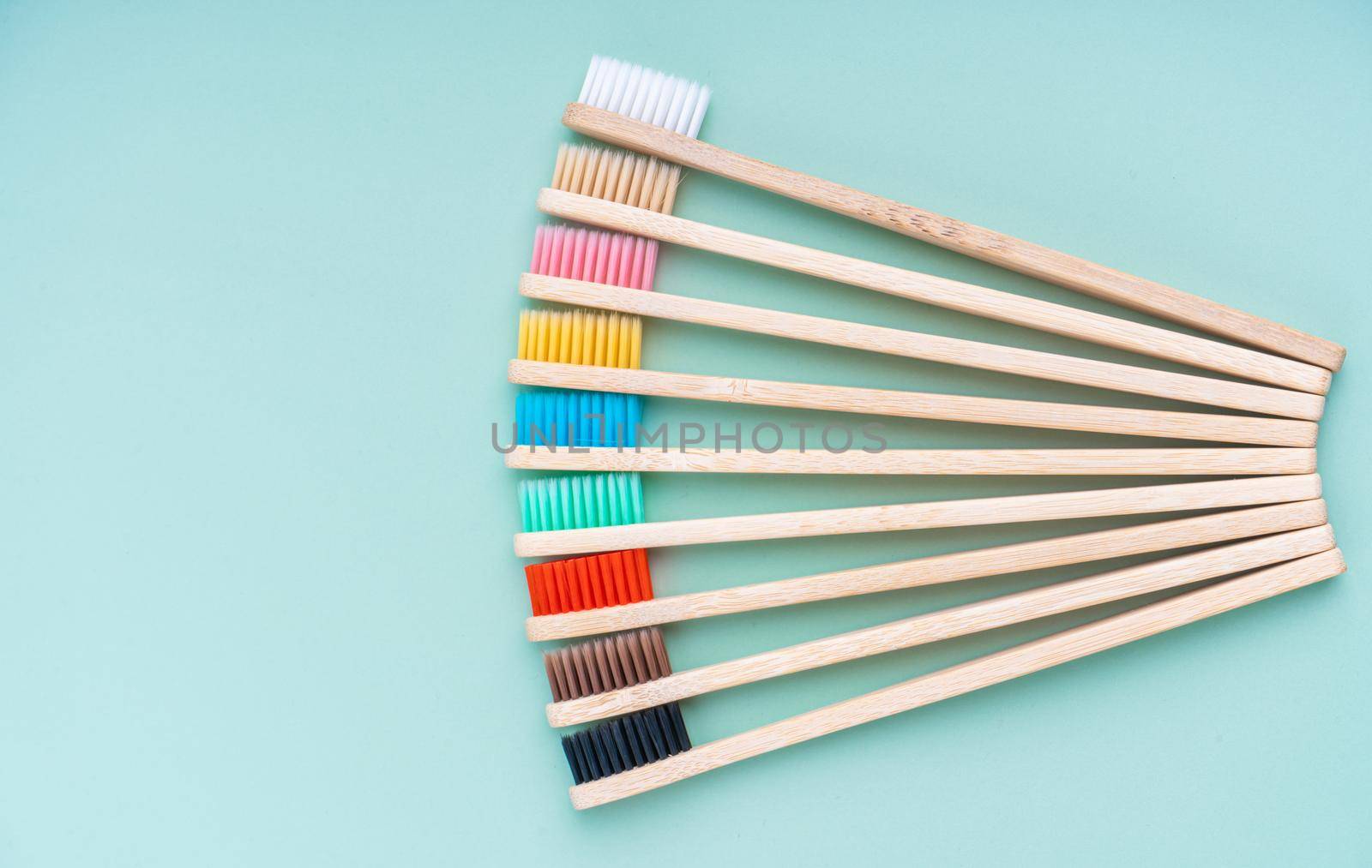 A set of Eco-friendly antibacterial toothbrushes made of bamboo wood on a light green background. Environmental care trends.