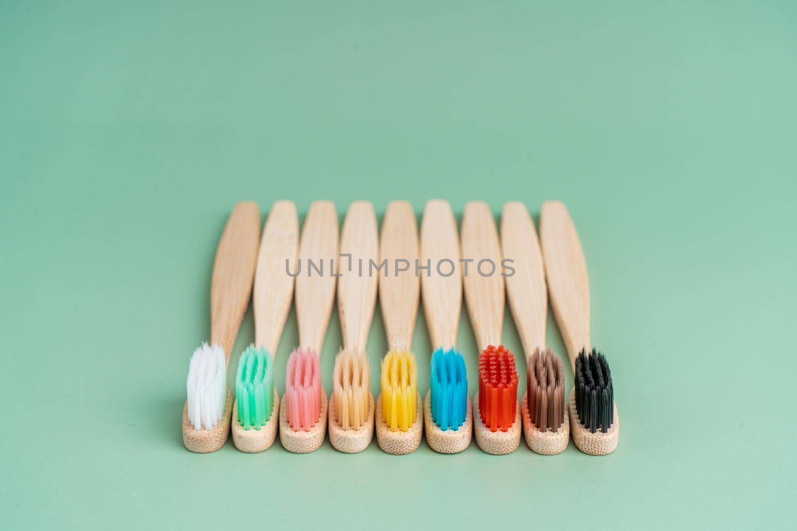 A set of Eco-friendly antibacterial toothbrushes made of bamboo wood on a light green background. Environmental care trends.