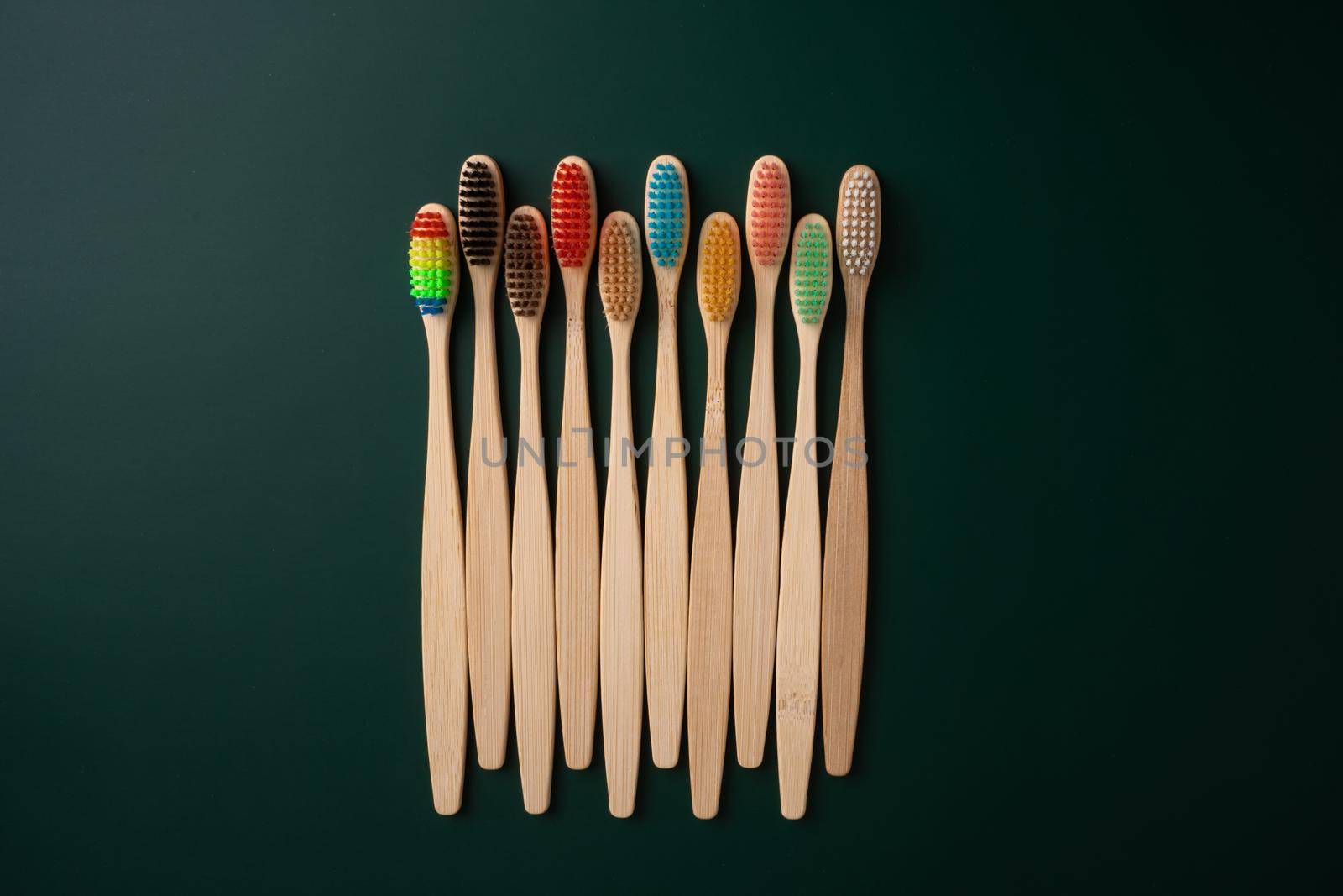 A set of Eco-friendly antibacterial toothbrushes made of bamboo wood on a dark green background. Environmental trends by Try_my_best